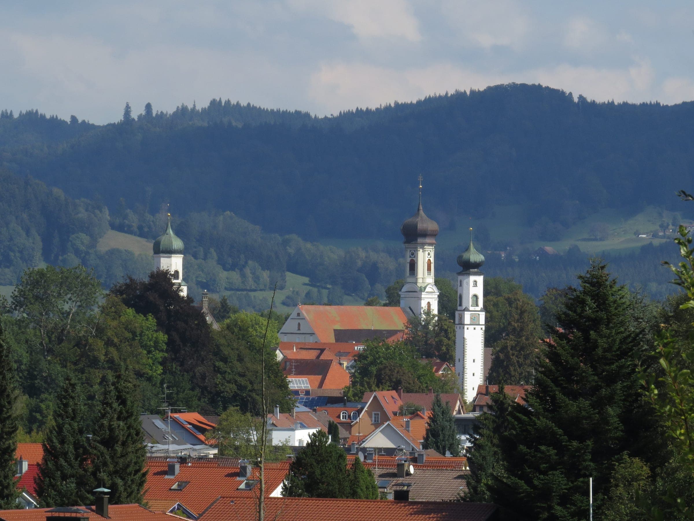 Blick auf Isny im Allgäu mit Kirchtürmen, dahinter die bewaldete Adelegg